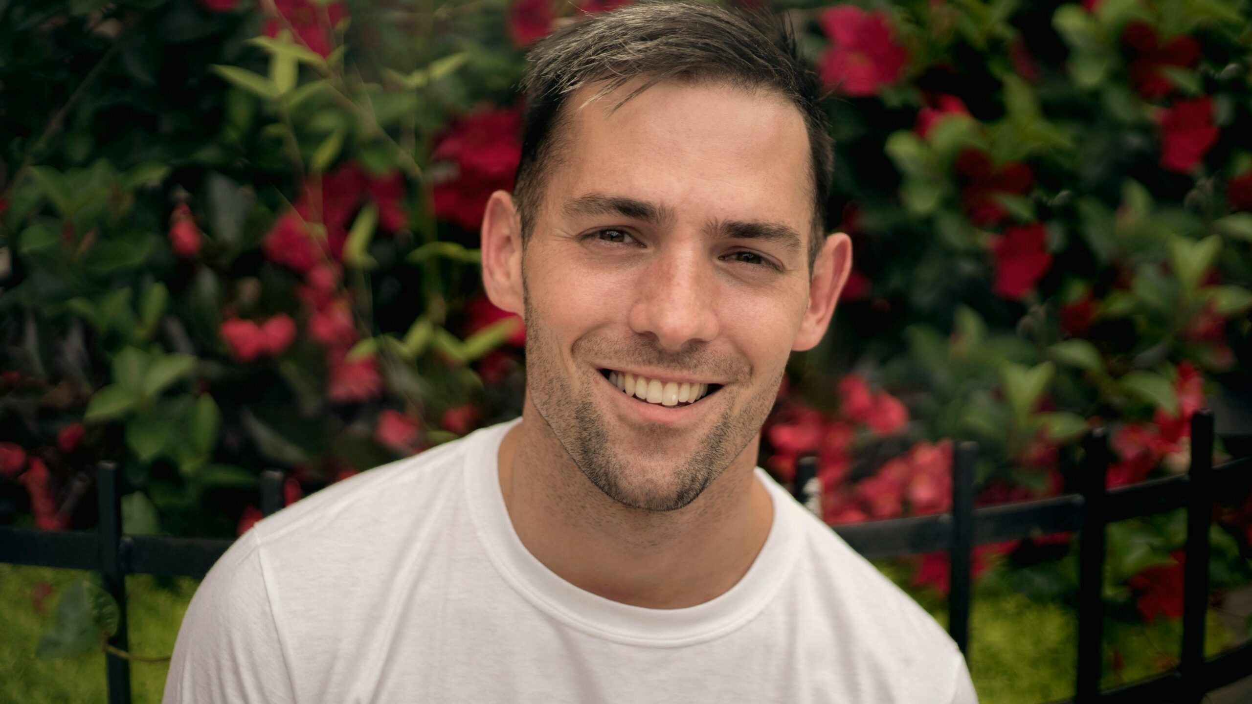 Portrait of a smiling man in front of vibrant flowers in Chicago.